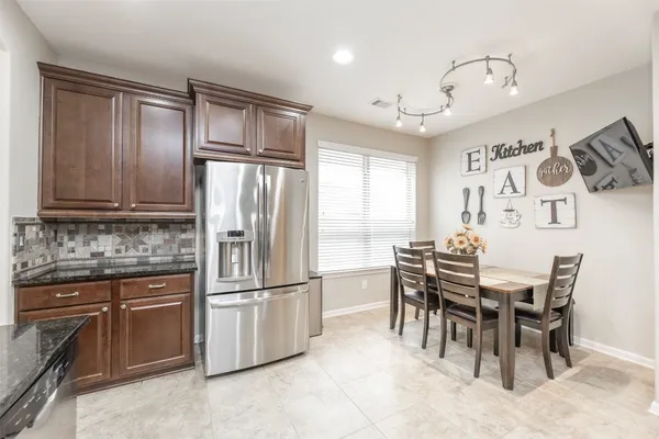 a kitchen with granite countertop stainless steel appliances a table and chairs in it