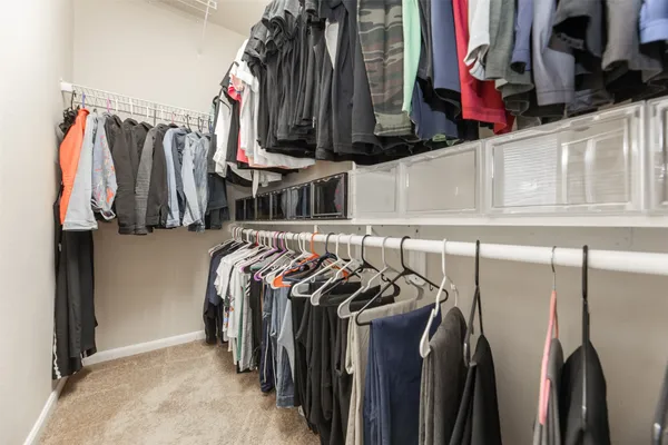 a view of walk in closet with clothes and shoes