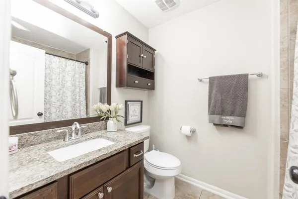 a bathroom with a granite countertop sink a toilet and mirror