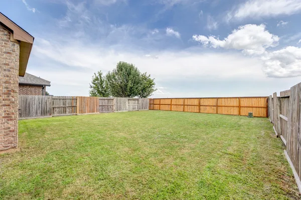 a brick house with a big yard and large trees