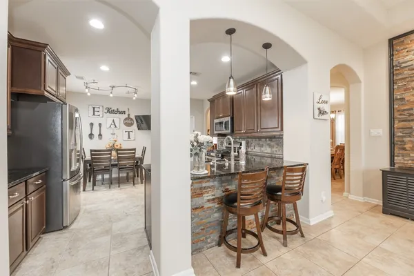 a kitchen with stainless steel appliances kitchen island granite countertop a refrigerator and cabinets