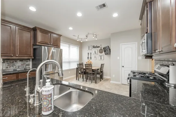 a kitchen with granite countertop a sink a stove and a refrigerator