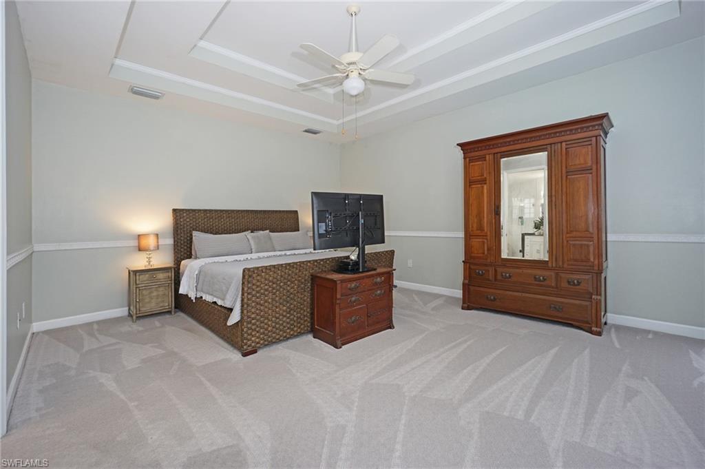 3188 Sundance Circle Naples, FL 34109 - Photo 22 of 39 a bedroom with a large bed and a chandelier