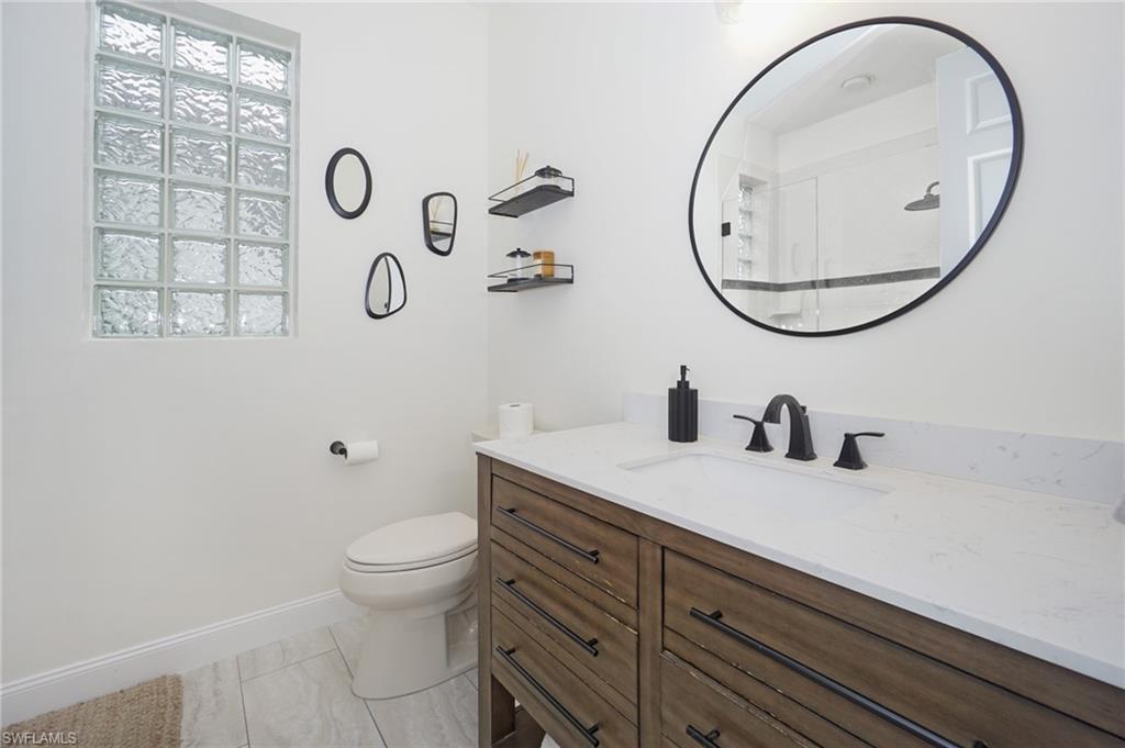 3188 Sundance Circle Naples, FL 34109 - Photo 29 of 39 a bathroom with a granite countertop toilet sink mirror and vanity