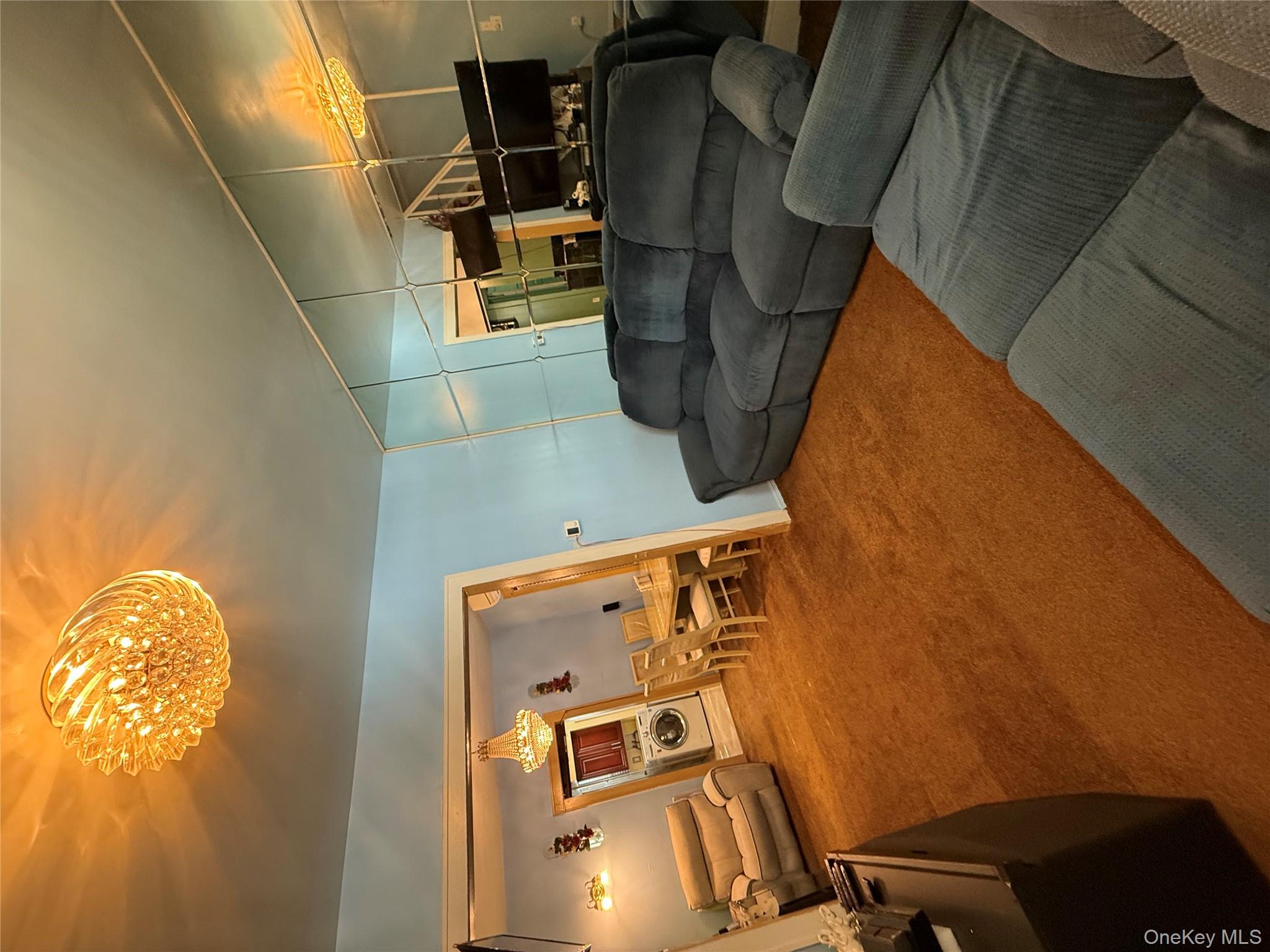 104-25 126th Street Queens, NY 11419 - Photo 11 of 22 Living room with carpet floors, washer / dryer, and a chandelier