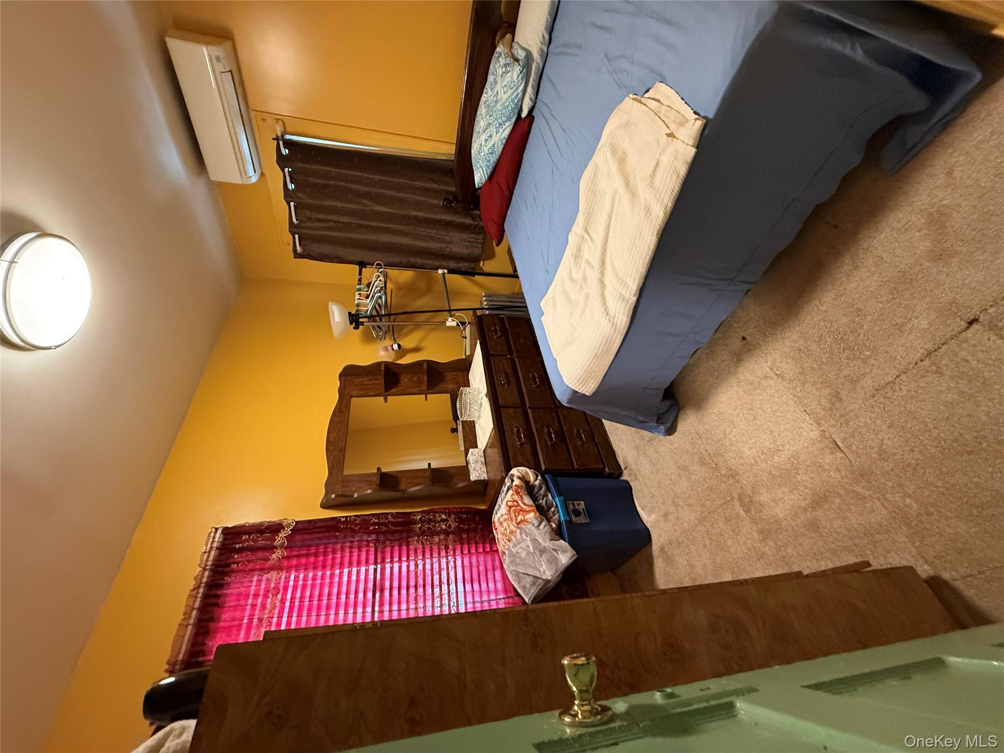 104-25 126th Street Queens, NY 11419 - Photo 5 of 22 Bedroom with light colored carpet and a wall mounted AC