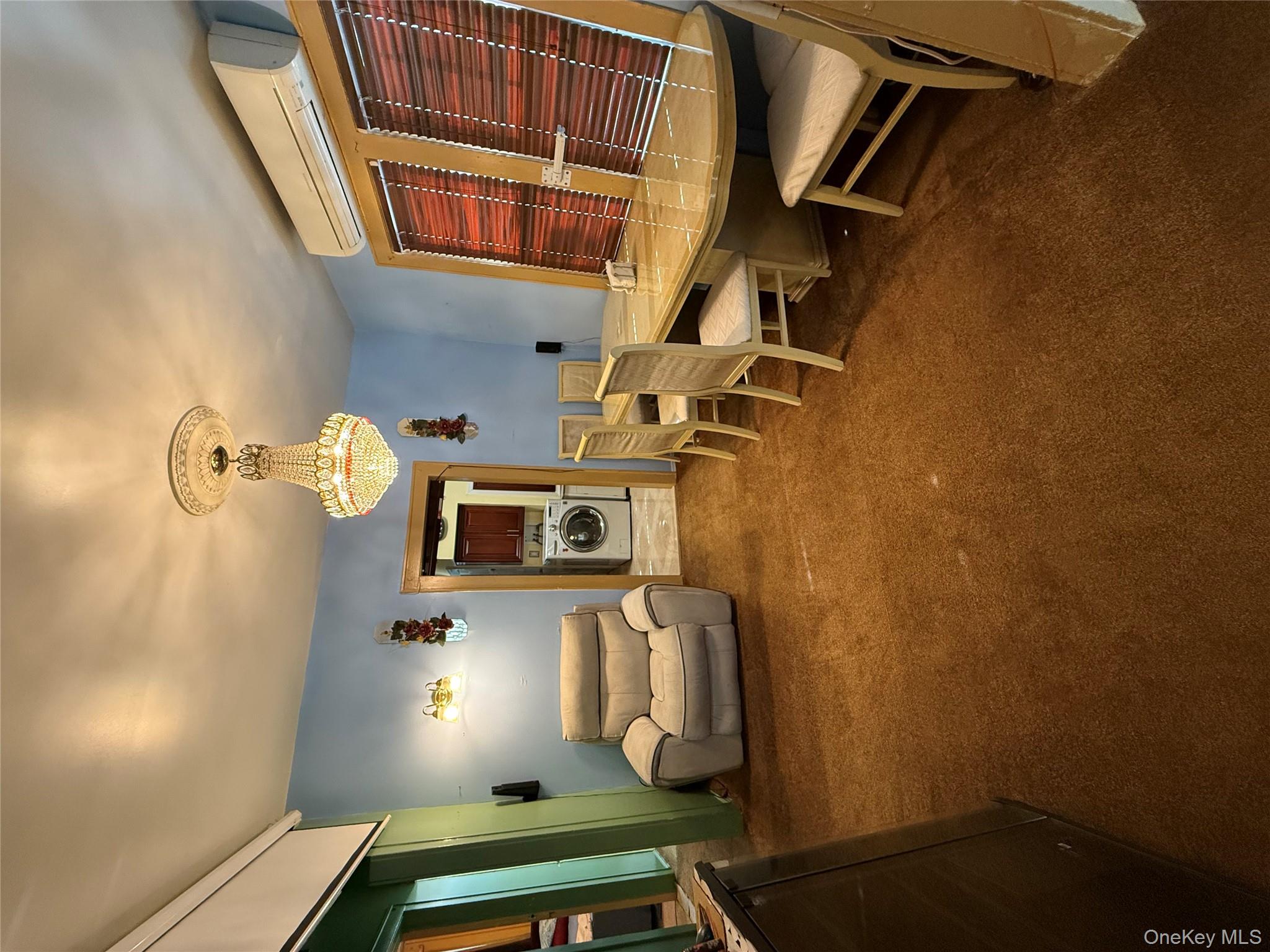 104-25 126th Street Queens, NY 11419 - Photo 8 of 22 Dining room featuring dark carpet, a wall mounted air conditioner, washer / dryer, and a chandelier