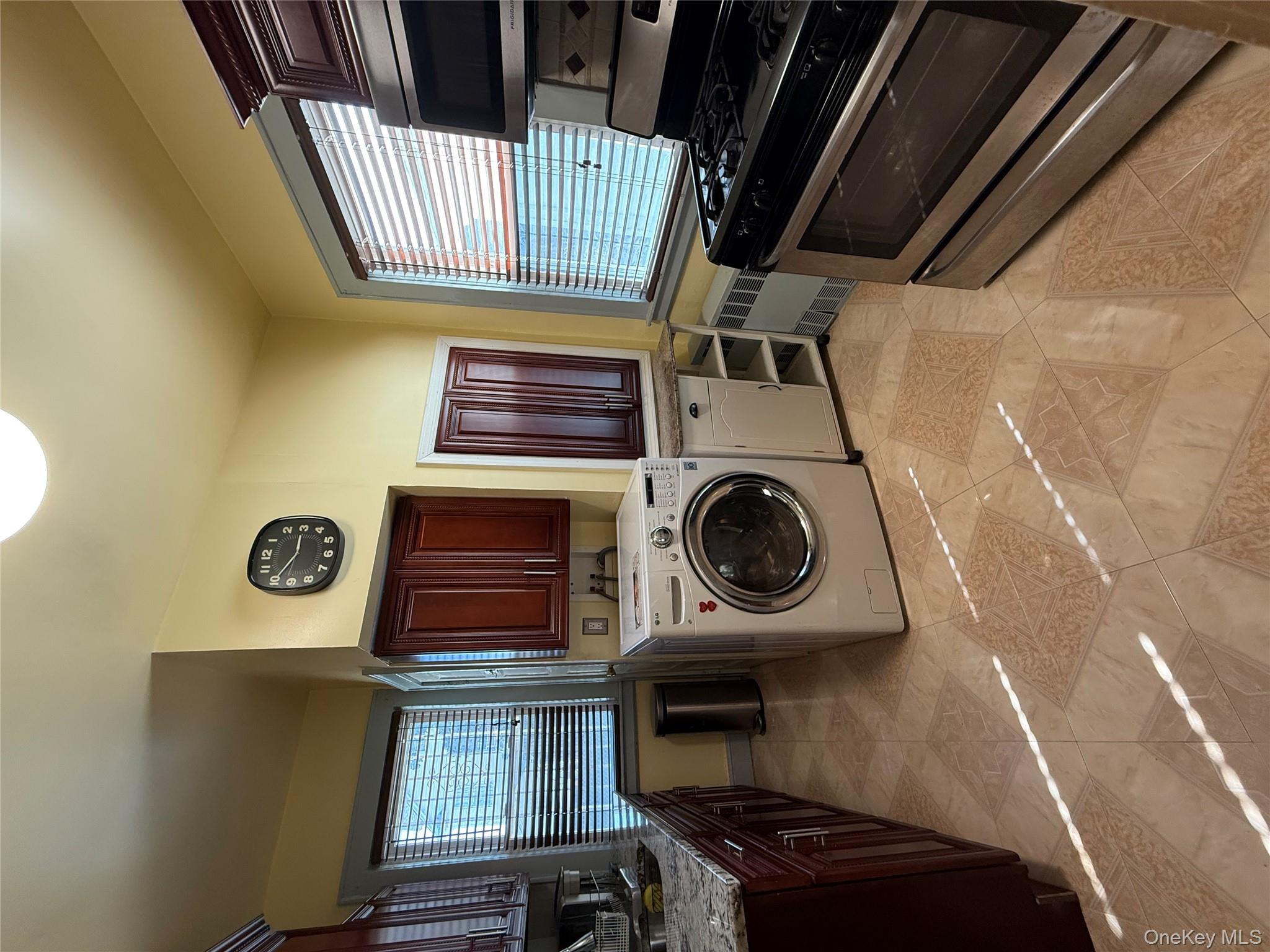 104-25 126th Street Queens, NY 11419 - Photo 10 of 22 Laundry room with washer / clothes dryer, healthy amount of natural light, radiator heating unit, and light tile patterned floors
