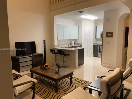 a living room with furniture a flat screen tv and kitchen view