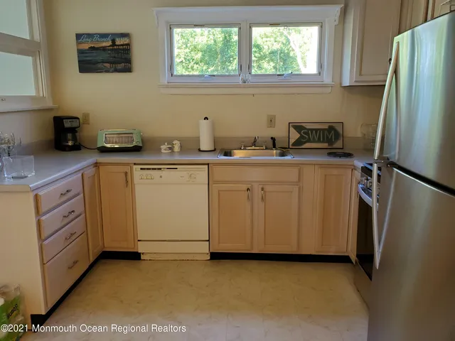 a kitchen with white cabinets and refrigerator