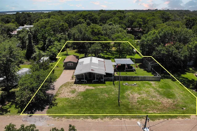 an aerial view of residential house with outdoor space and trees all around