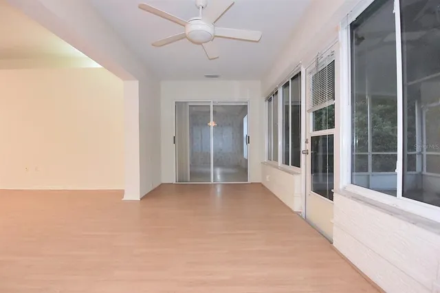 a view of an empty room with window and wooden floor