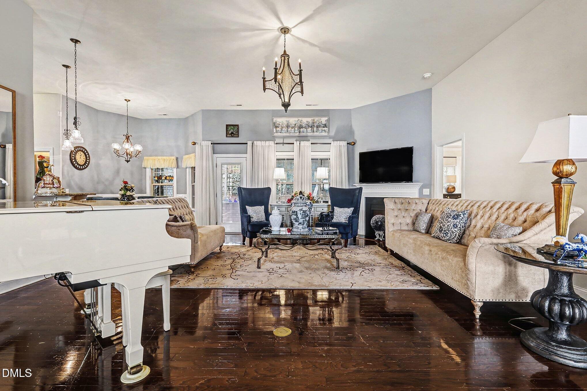 128 Dereham Lane Garner, NC 27529 - Photo 3 of 29 a living room with furniture a chandelier and a flat screen tv
