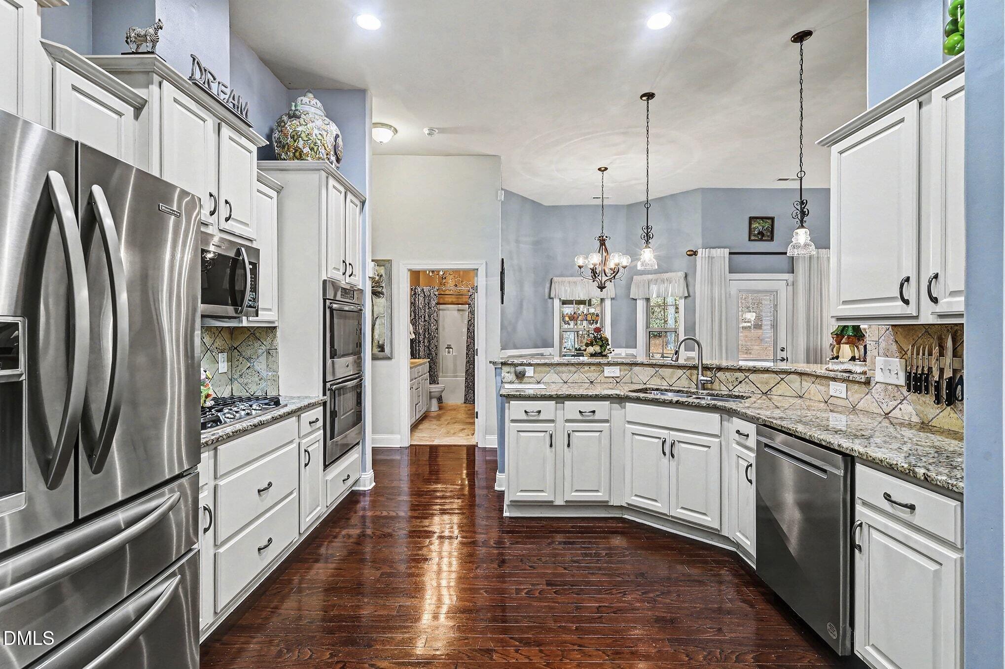 128 Dereham Lane Garner, NC 27529 - Photo 10 of 29 a kitchen with stainless steel appliances granite countertop a refrigerator a oven and white cabinets with wooden floors