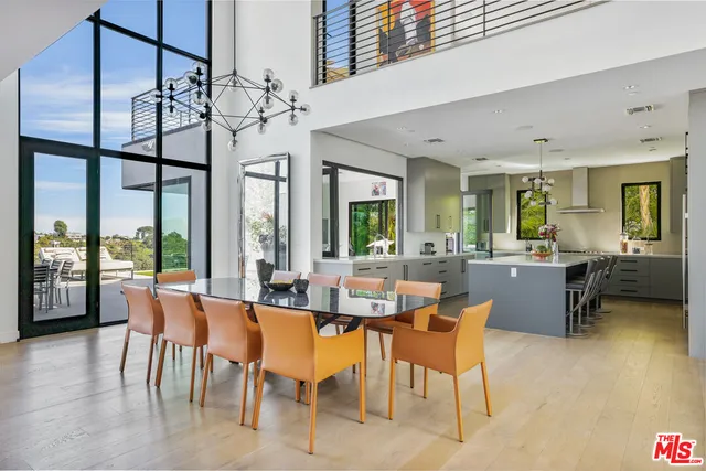 a large white kitchen with a large island in the center and stainless steel appliances
