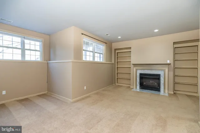 an empty room with windows and fireplace