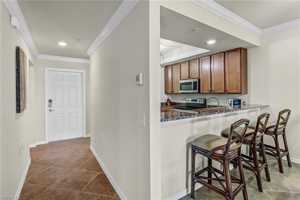 9521 Avellino Way, Unit 2415 Naples, FL 34113 - Photo 27 of 48 a view of a kitchen with kitchen island table and chairs