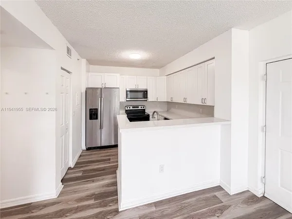 a kitchen with wooden floor and electronic appliances
