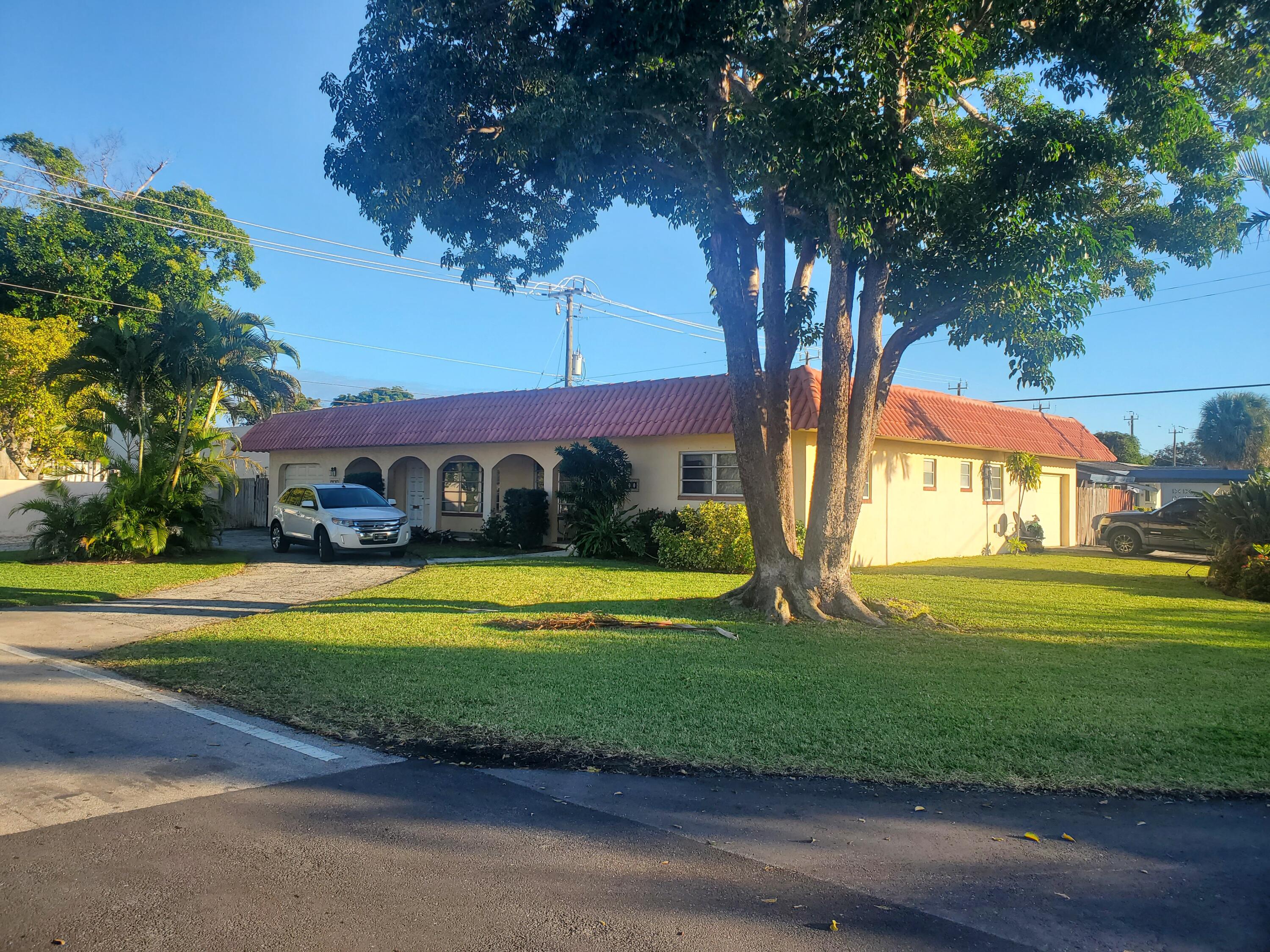 a view of a big house with a large trees and plants