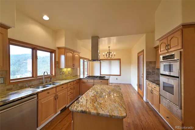 a large kitchen with kitchen island granite countertop a large window and stainless steel appliances
