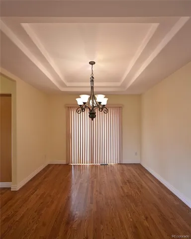 a view of a room with wooden floor chandelier and windows