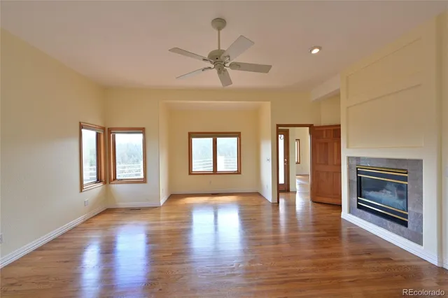 a view of an empty room with a window and wooden floor