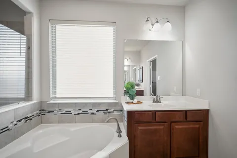 a spacious bathroom with a tub sink shower and mirror