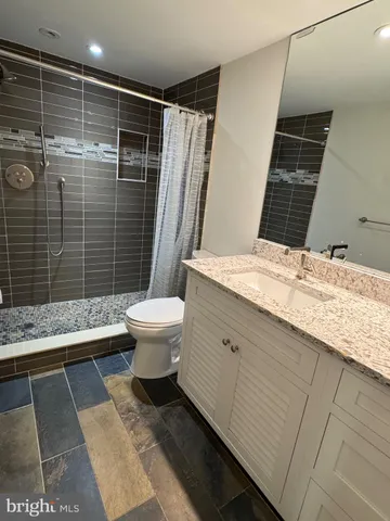 a bathroom with a granite countertop sink toilet and shower