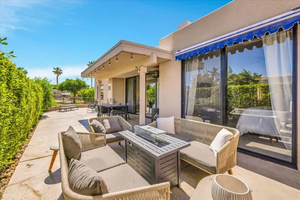 a view of a patio with couches and a table and chairs with floor to ceiling window and potted plants