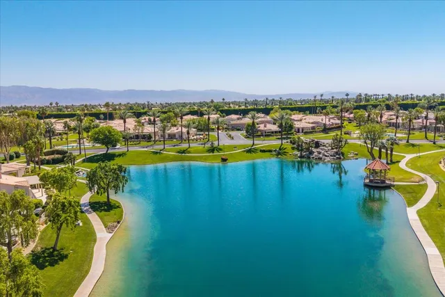 a view of a swimming pool with a lawn chairs potted plants and palm trees