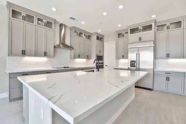 a large kitchen with kitchen island a large counter top wooden cabinets and appliances