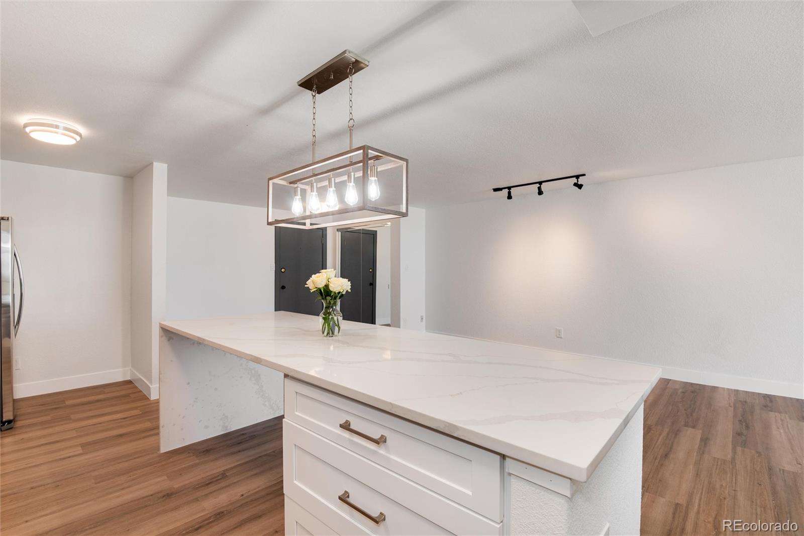 2 Adams Street, Unit 1504 Denver, CO 80206 - Photo 12 of 43 a kitchen with a sink a chandelier and wooden floor