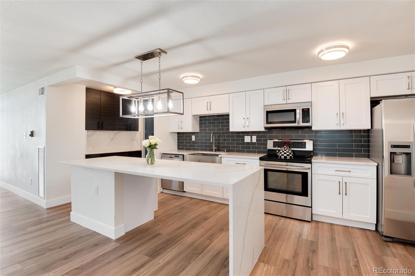 2 Adams Street, Unit 1504 Denver, CO 80206 - Photo 7 of 43 a kitchen with stainless steel appliances a microwave a stove a sink dishwasher a refrigerator and white cabinets with wooden floor