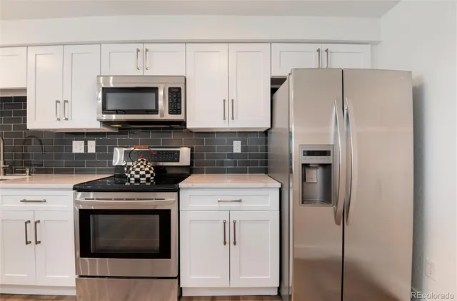 a kitchen with cabinets stainless steel appliances and a wooden floor