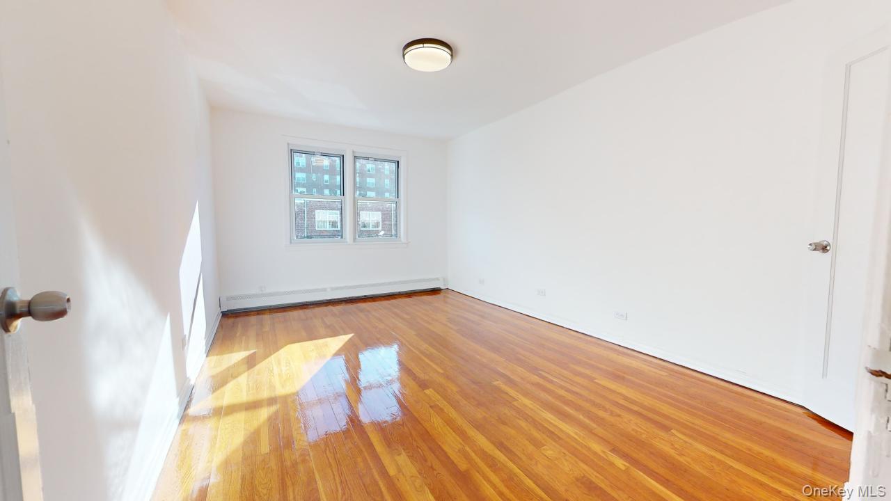 105-28 63rd Road, Unit 2 Queens, NY 11375 - Photo 17 of 30 an empty room with wooden floor and windows