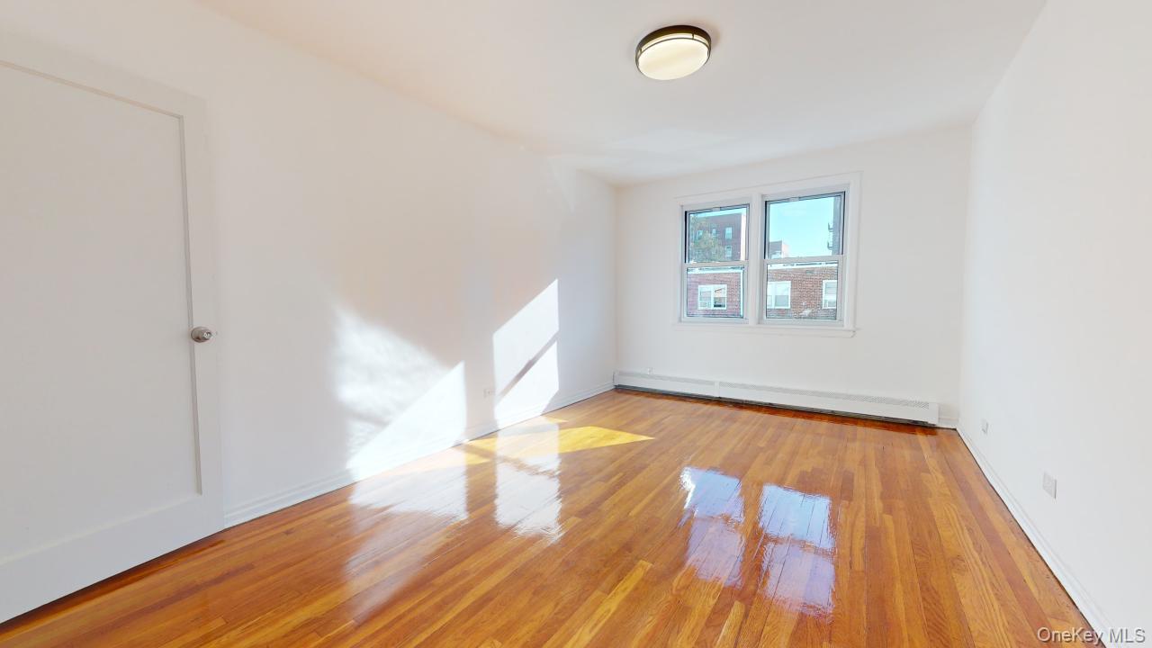 105-28 63rd Road, Unit 2 Queens, NY 11375 - Photo 18 of 30 an empty room with wooden floor and windows