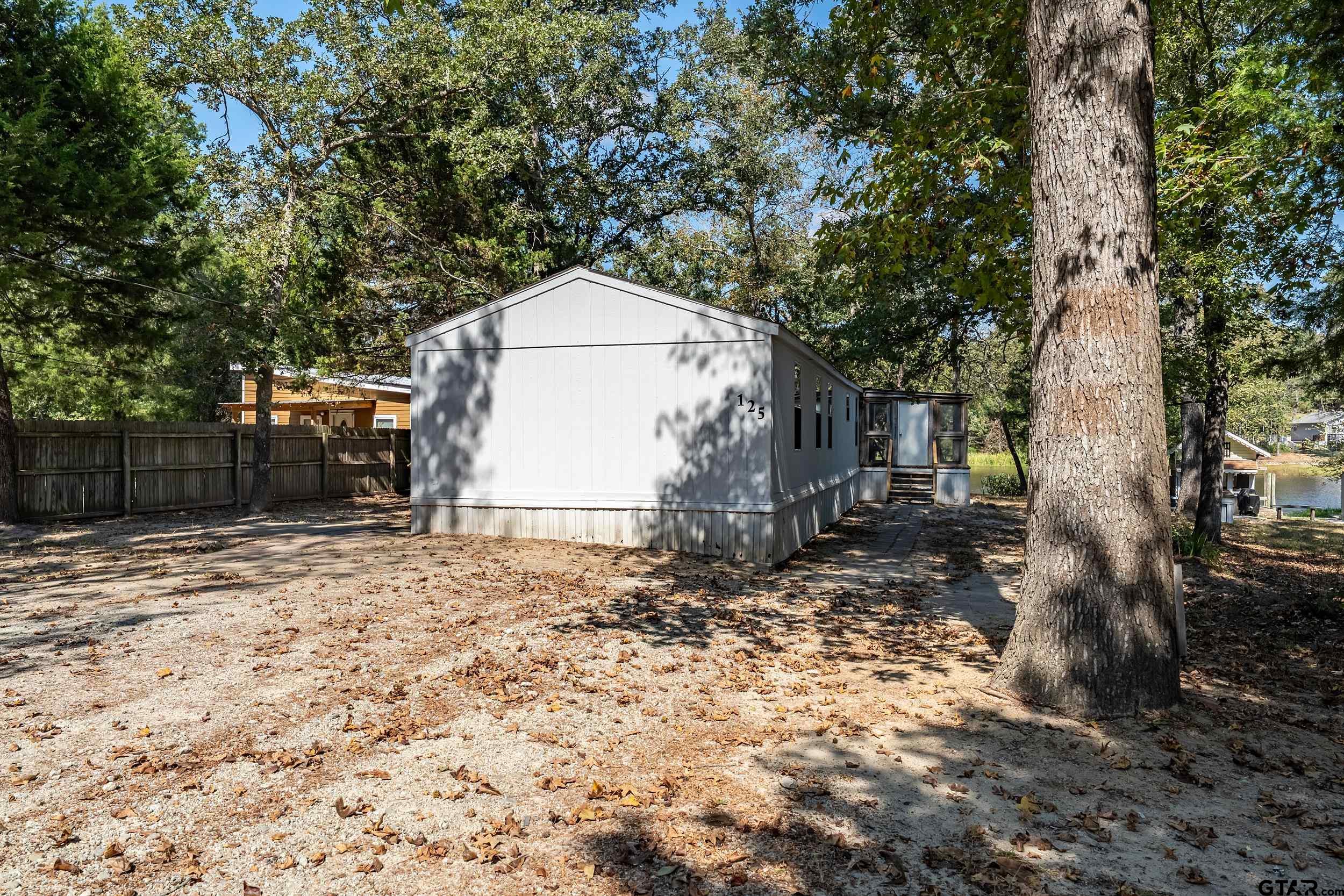 125 Ridgewood Lane Murchison, TX 75778 - Photo 34 of 46 a backyard of a house with large trees and a wooden fence