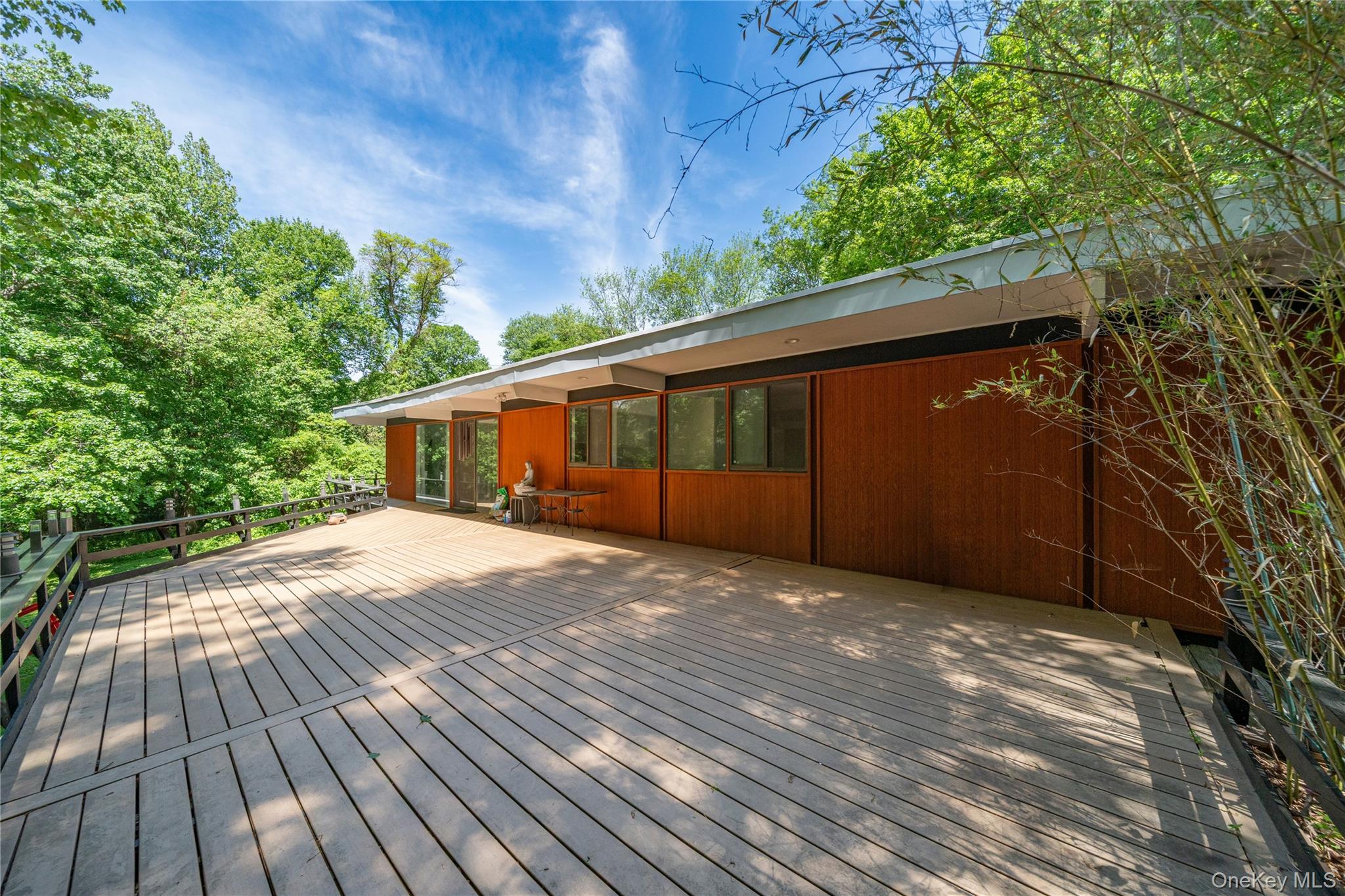 4 Half Mile Road Armonk, NY 10504 - Photo 11 of 28 Sprawling wraparound Trex deck with peaceful wooded views, seamless sliders from the dining area, and ample space for outdoor entertaining and relaxing.