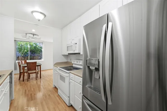 a kitchen with stainless steel appliances granite countertop a refrigerator a stove a sink and a dining table with wooden floor