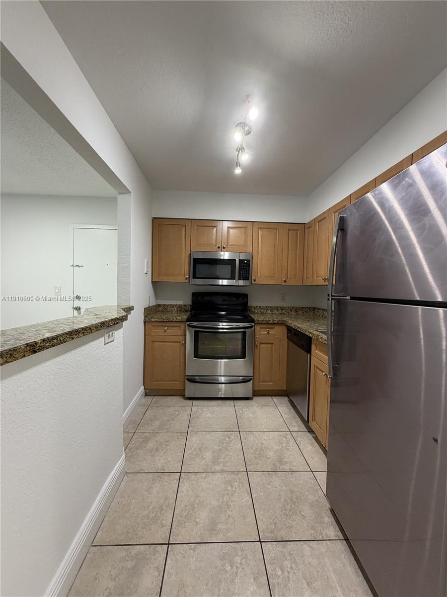 5112 Northwest 79th Avenue, Unit 304 Doral, FL 33166 - Photo 8 of 15 a kitchen with granite countertop a refrigerator and a stove