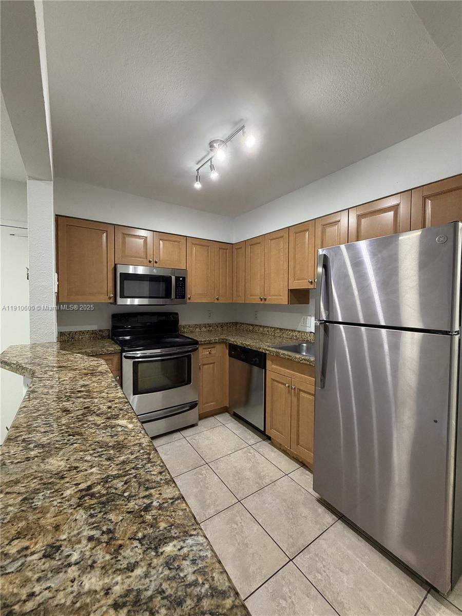 5112 Northwest 79th Avenue, Unit 304 Doral, FL 33166 - Photo 9 of 15 a kitchen with granite countertop a refrigerator and a stove top oven