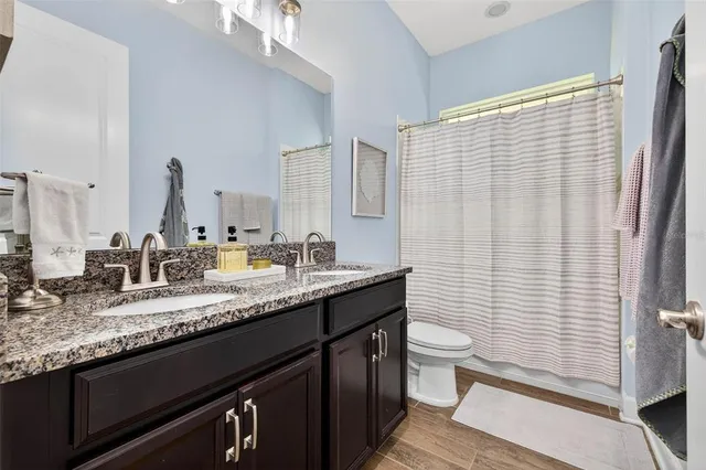 a bathroom with a granite countertop sink a toilet and a mirror