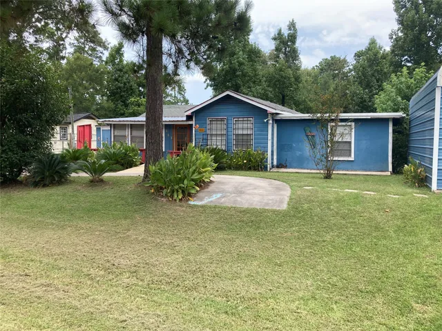 a backyard of a house with plants and large tree