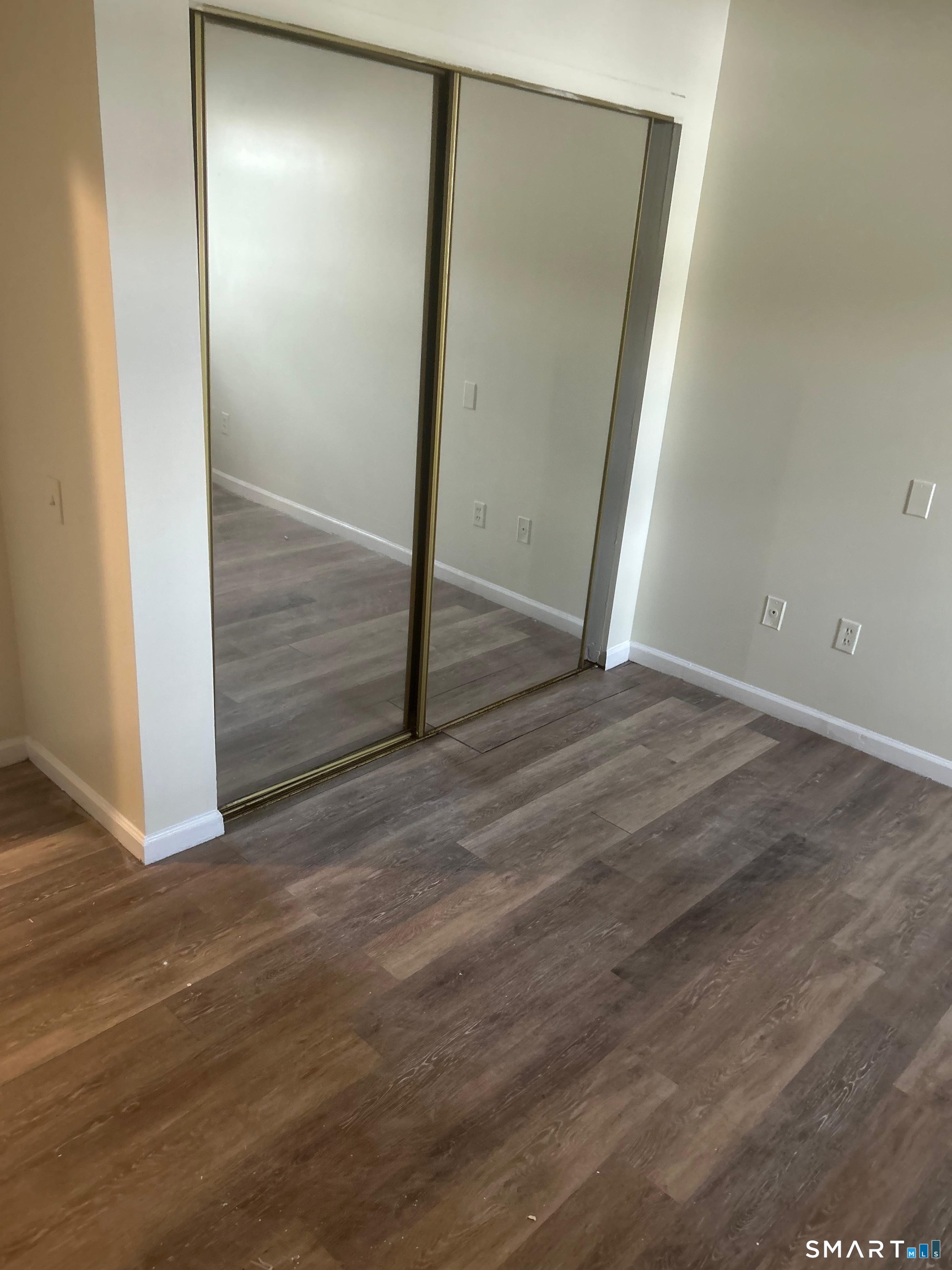 30 Stevens Street, Unit 105 Bridgeport, CT 06606 - Photo 7 of 8 an empty room with wooden floor and mirror