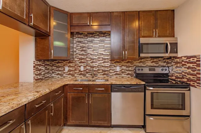 a kitchen with stainless steel appliances granite countertop a stove a sink and a microwave