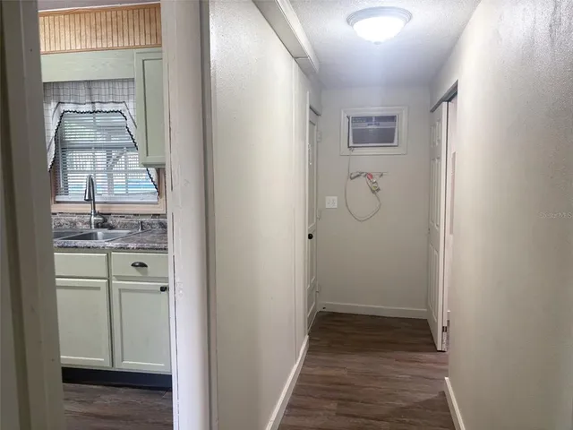 a view of a hallway with wooden floor and a bathroom