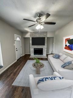 4512 Sycamore Street Dallas, TX 75204 - Photo 6 of 23 Living area with a stone fireplace, a textured ceiling, dark wood-style flooring, and ceiling fan