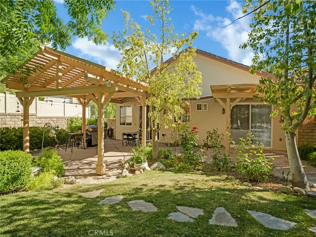 a view of a patio with table and chairs potted plants and large tree