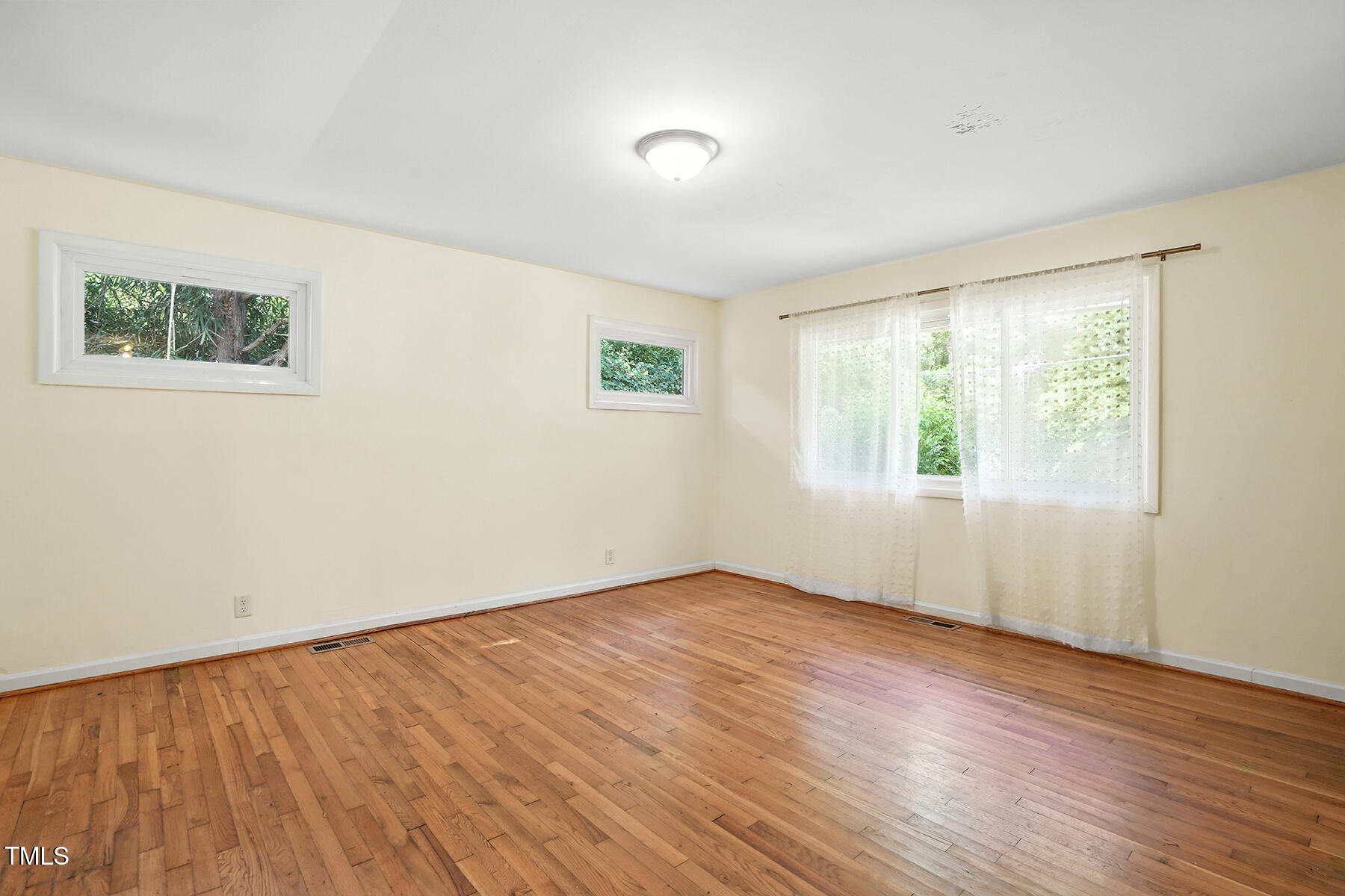 912 Dixie Trail Raleigh, NC 27607 - Photo 5 of 27 a view of an empty room with wooden floor and a window