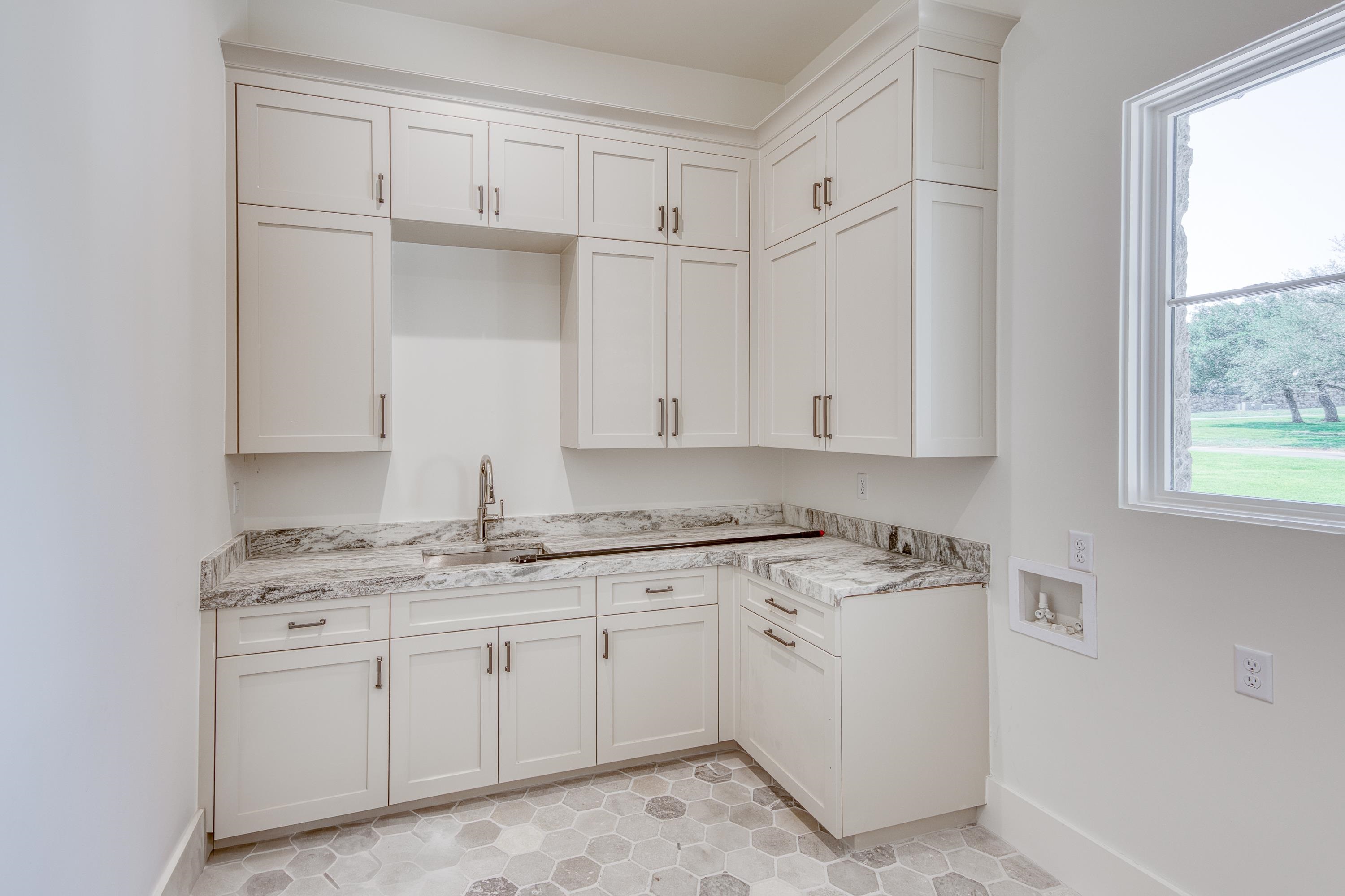 369 La Serena Loop Horseshoe Bay, TX 78657 - Photo 22 of 30 a kitchen with white cabinets and white appliances